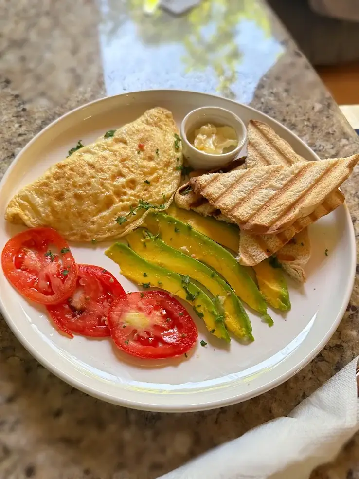 Petit-déjeuner : omelette, avocat, tomate et pain grillé